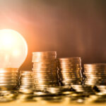 Stack_of_coins_and_light_bulb_for_saving_money_concept,_Creative_ideas_of_business_planning,_success_in_the_future.